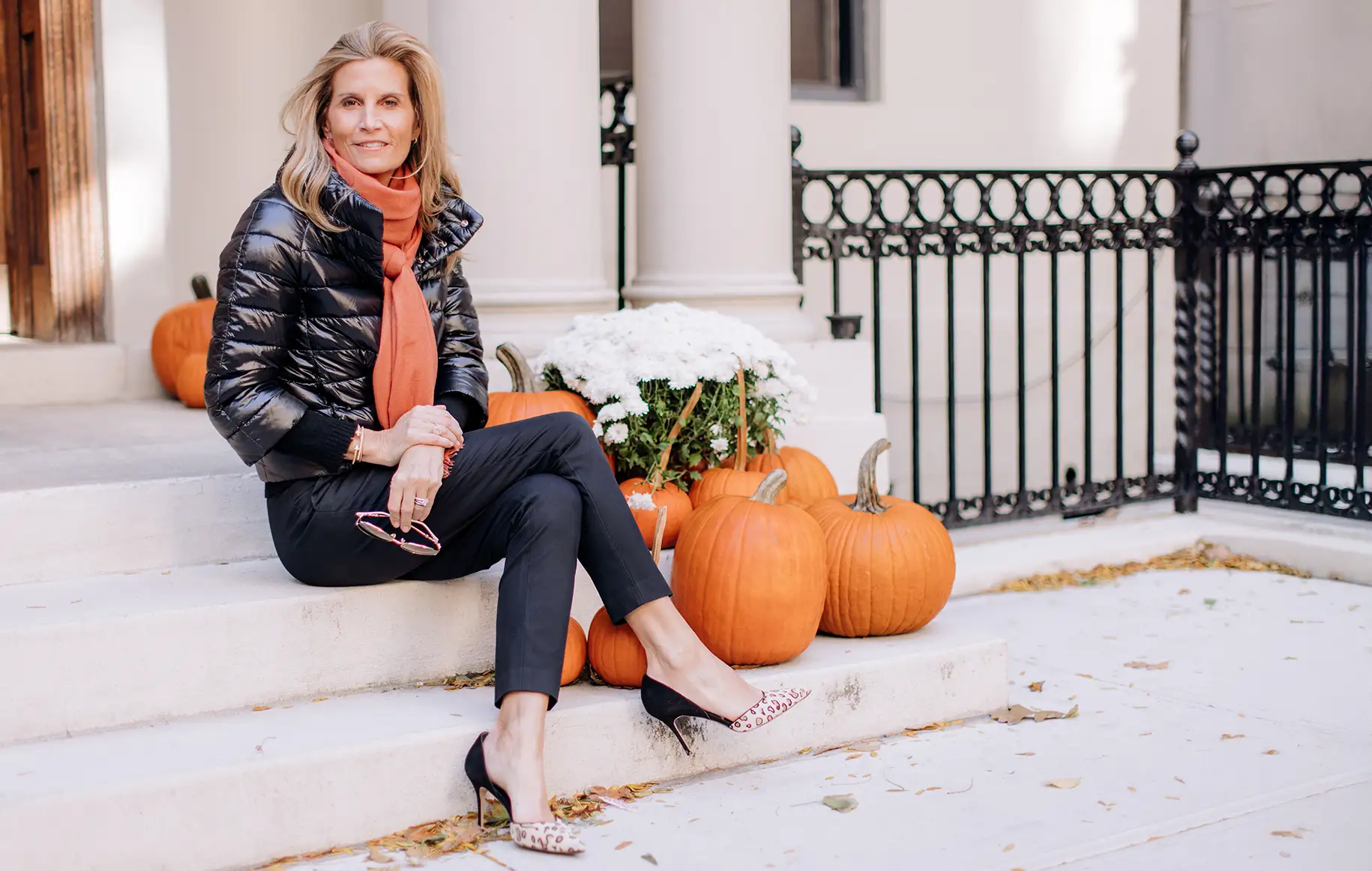 Women sitting on stairs dresses in black with fall pumpkins